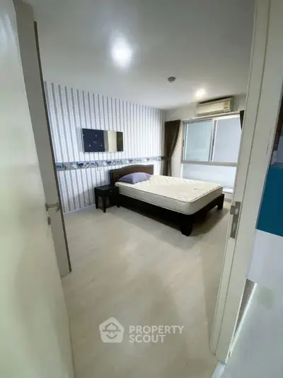 Spacious bedroom with modern decor and large window for natural light.