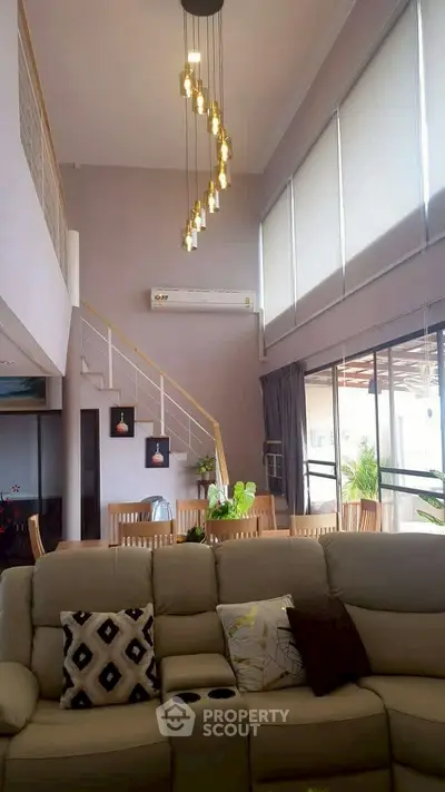 Luxurious living room with high ceilings, modern lighting, and elegant decor in a spacious open-plan design.