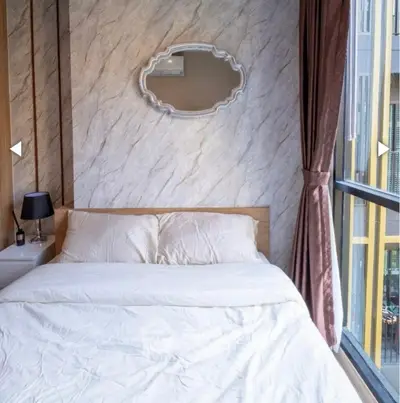 Cozy bedroom with modern decor and large window offering natural light.
