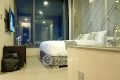 Modern bedroom with large window and stylish decor, perfect for urban living.
