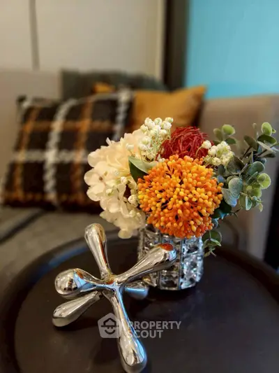Stylish living room decor with vibrant floral arrangement and modern metallic sculpture on a sleek table.