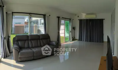 Spacious living room with modern leather sofa and large windows offering natural light.
