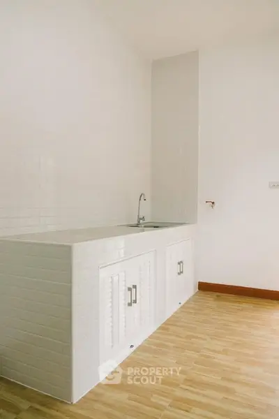 Minimalist kitchen with white cabinetry and wooden flooring