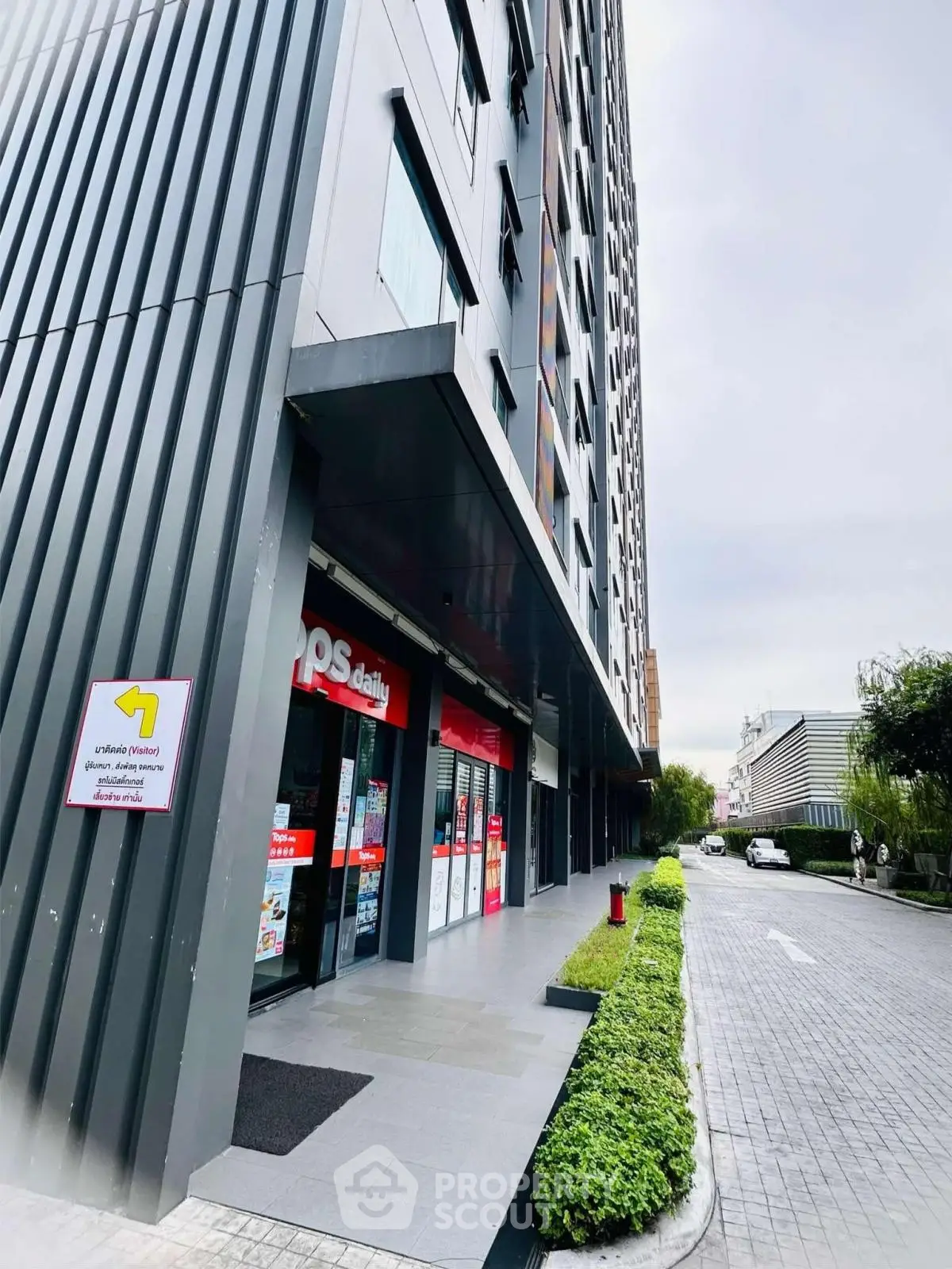Modern commercial building exterior with retail store entrance and landscaped walkway