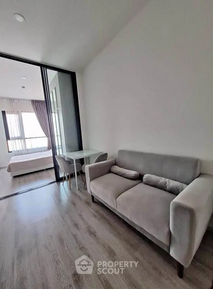 Modern apartment with cozy living room and bedroom, featuring sleek furniture and natural light.