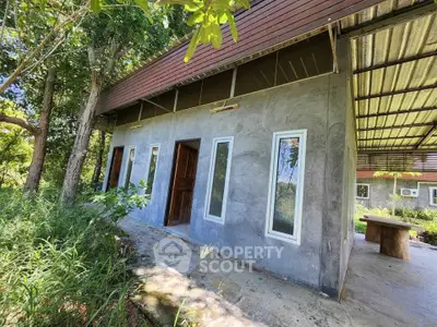 Charming rustic home with modern design in lush green setting, featuring large windows and covered patio.