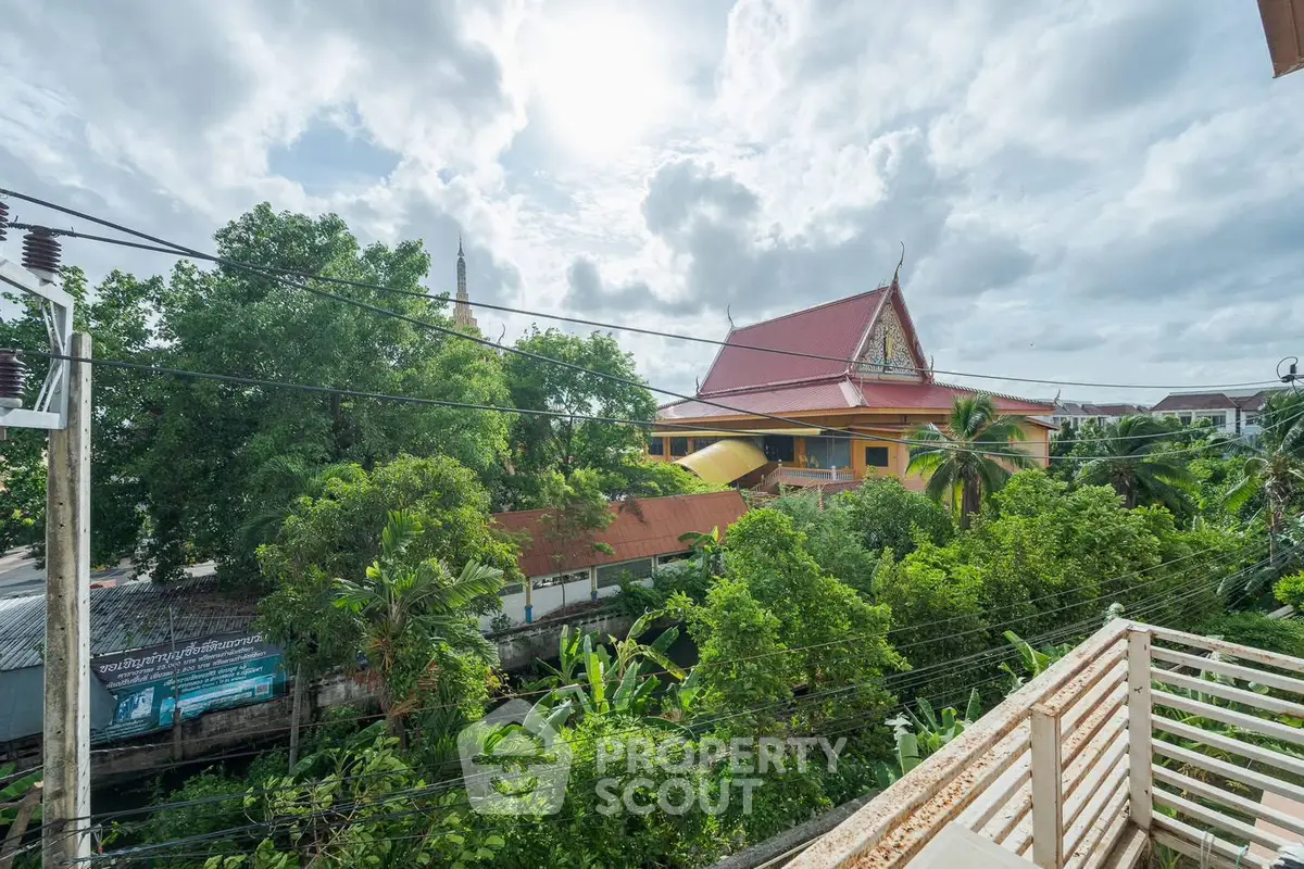 Stunning view from balcony overlooking lush greenery and traditional architecture under a cloudy sky.