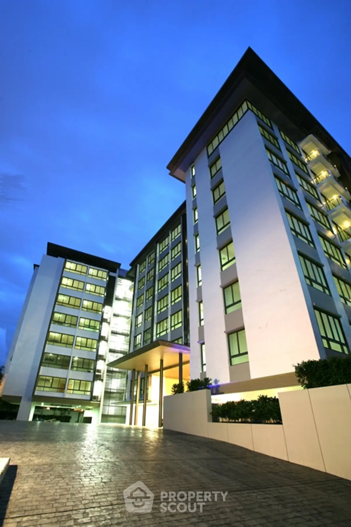 Modern high-rise building with sleek architecture and illuminated windows at dusk.