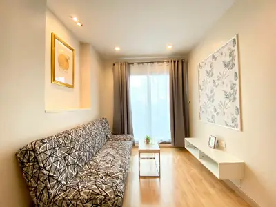 Modern living room with stylish sofa and wall art, featuring natural light and wooden flooring.