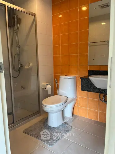Modern bathroom with orange tiles and glass shower enclosure