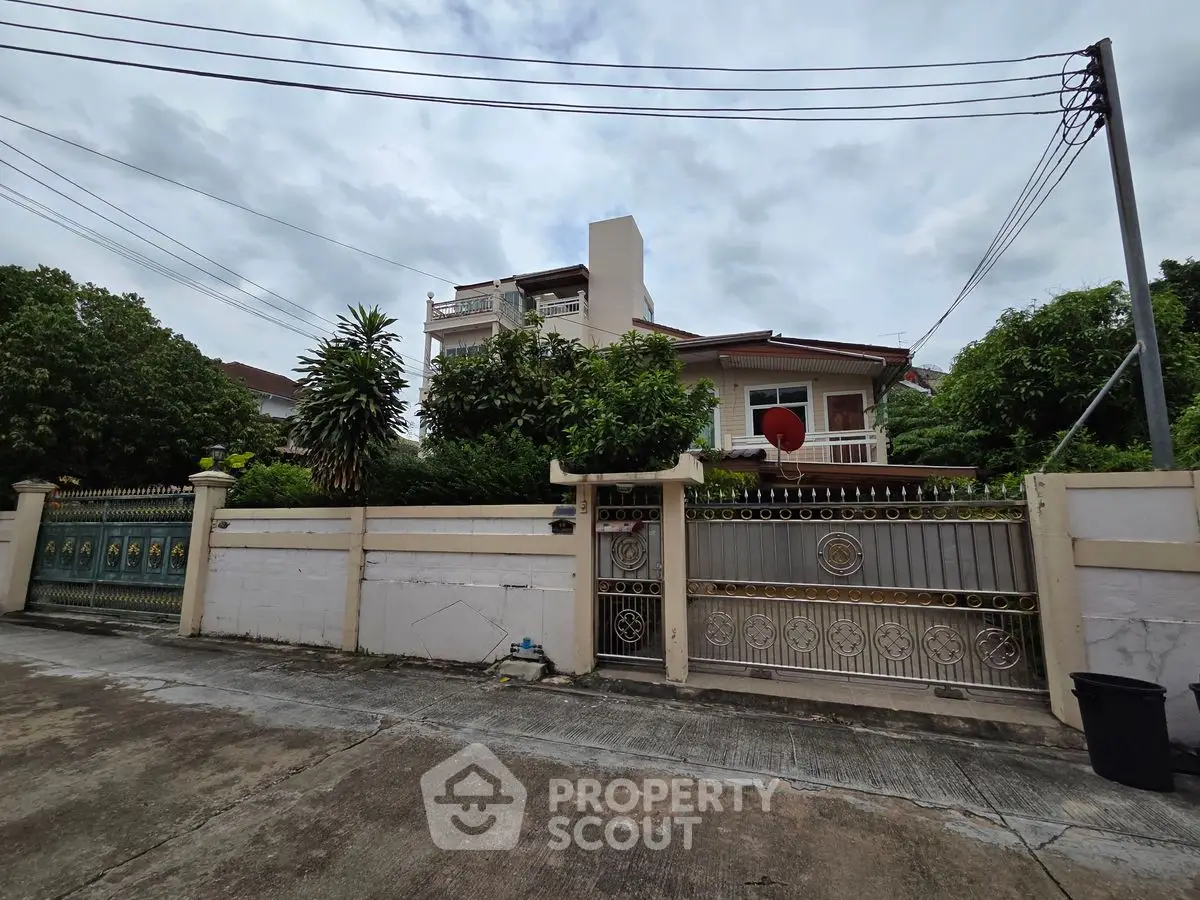 Charming suburban house with lush greenery and secure gated entrance.