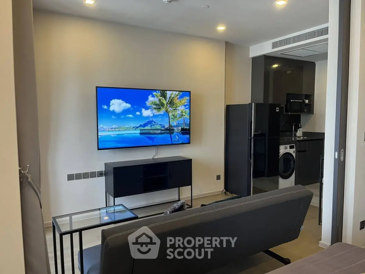 Modern living room with sleek kitchen, featuring a wall-mounted TV and stylish furniture.