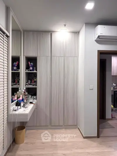 Modern bedroom with built-in wardrobe and vanity area, featuring sleek design and ample storage.