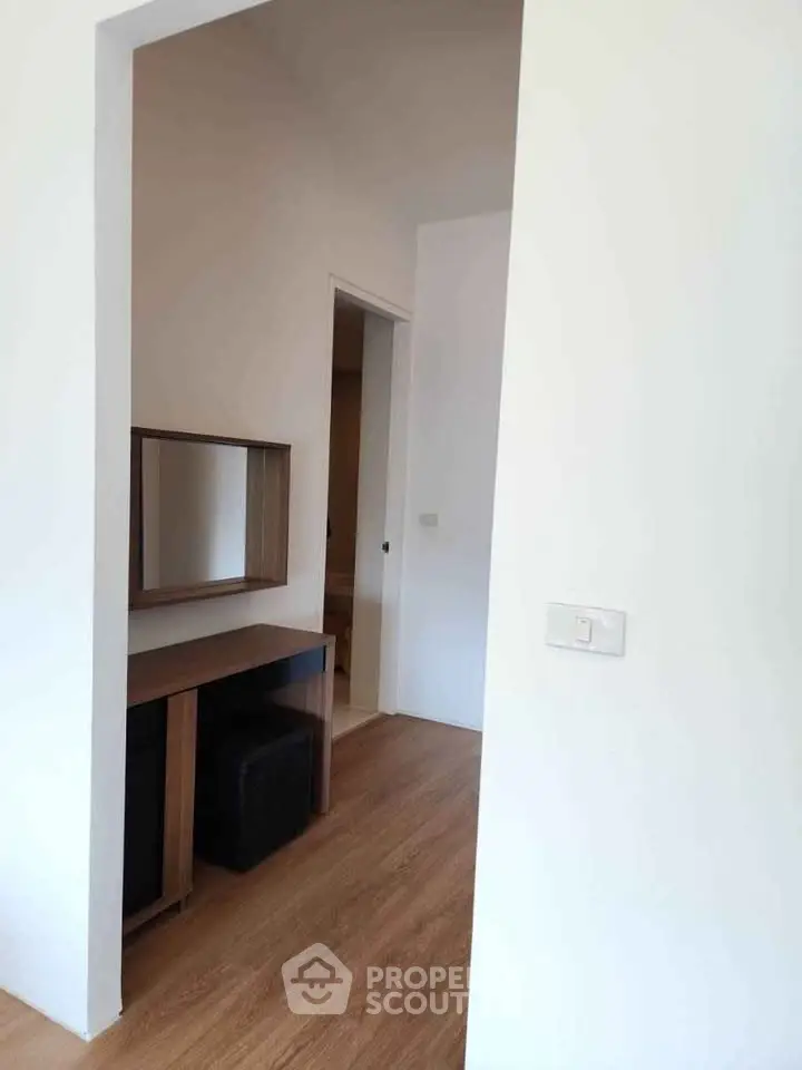 Modern interior with wooden flooring and minimalist furniture, featuring a stylish mirror and desk setup.