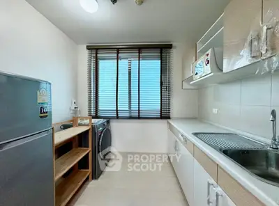 Modern kitchen with sleek appliances and ample storage space, featuring a washing machine and large window.