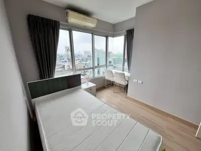 Bright bedroom with large windows and city view, featuring a bed and study area.