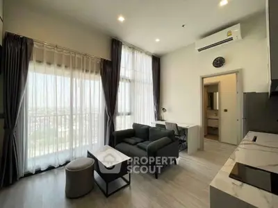 Modern living room with large windows and stylish furniture in high-rise apartment.