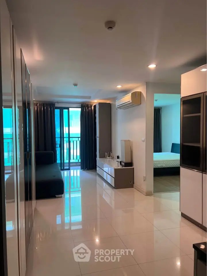 Modern apartment interior with sleek design and spacious layout, featuring a living area and bedroom with balcony access.