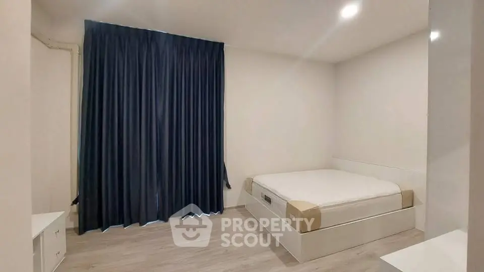 Minimalist bedroom with modern bed and dark curtains, perfect for a cozy retreat.