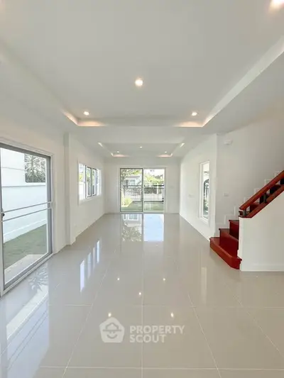 Spacious modern living room with large windows and glossy tiled floors, perfect for natural light and open living.