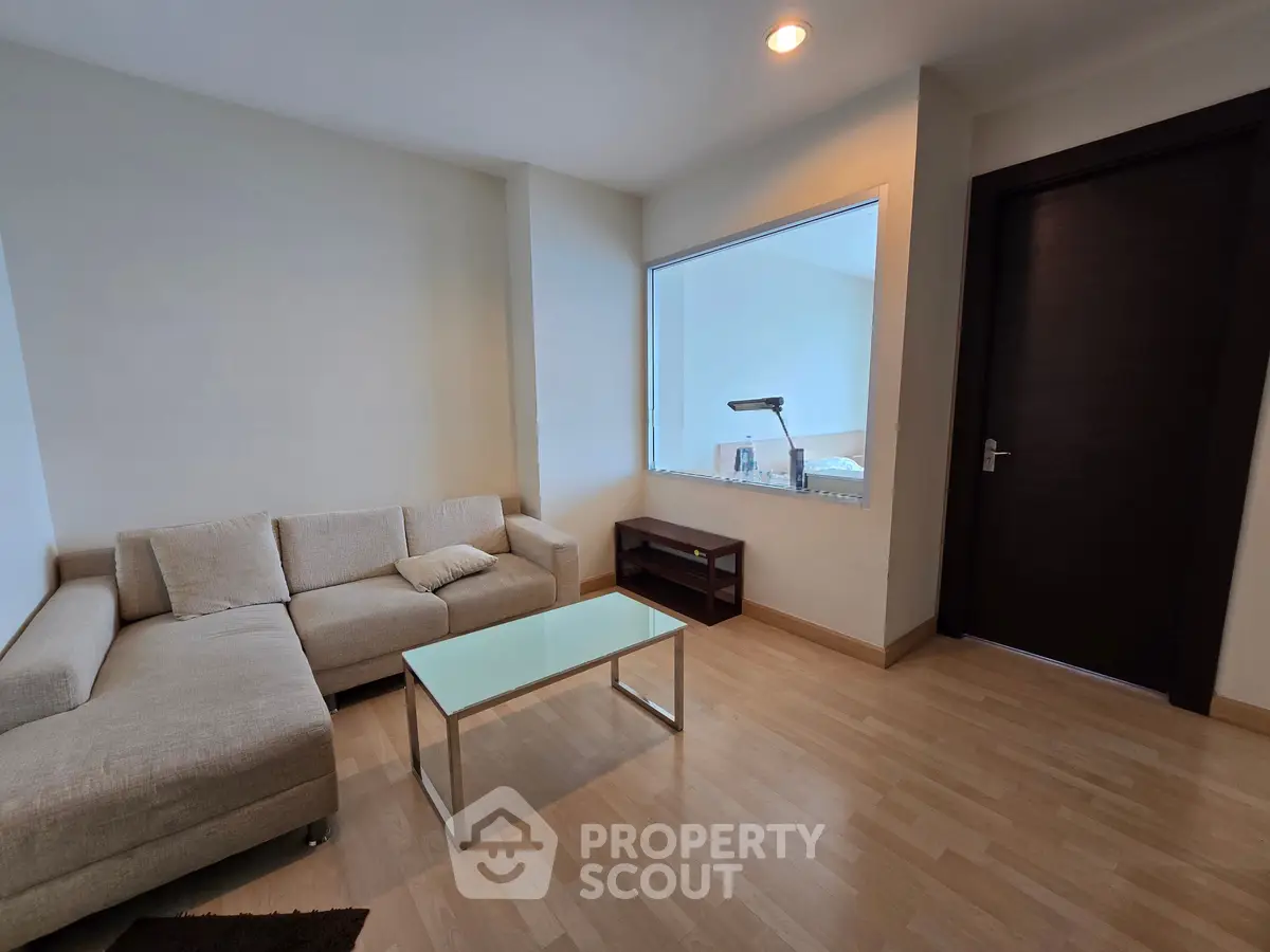 Modern living room with cozy beige sofa and glass coffee table, perfect for relaxation.