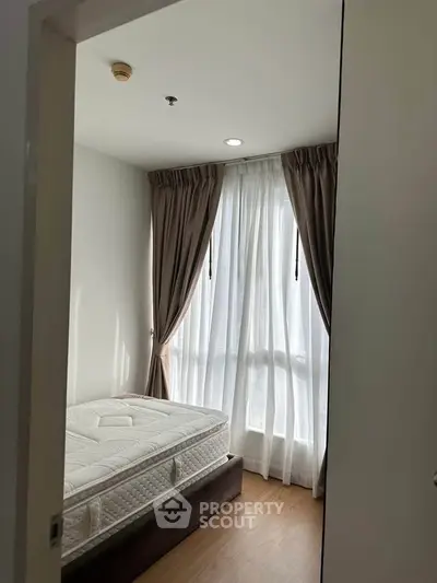 Cozy bedroom with natural light and elegant curtains, perfect for relaxation.