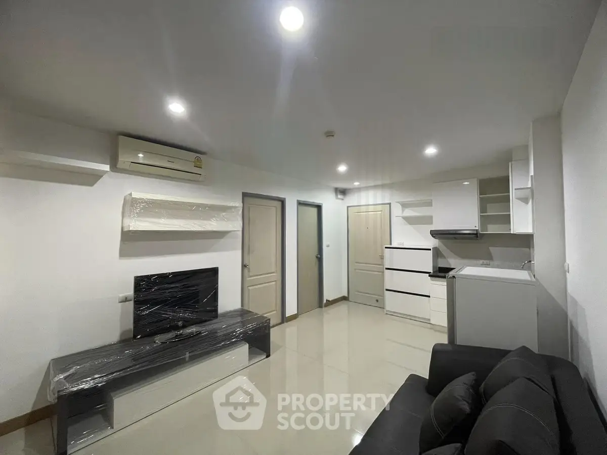 Modern living room with sleek furniture and open kitchen layout in a stylish apartment.