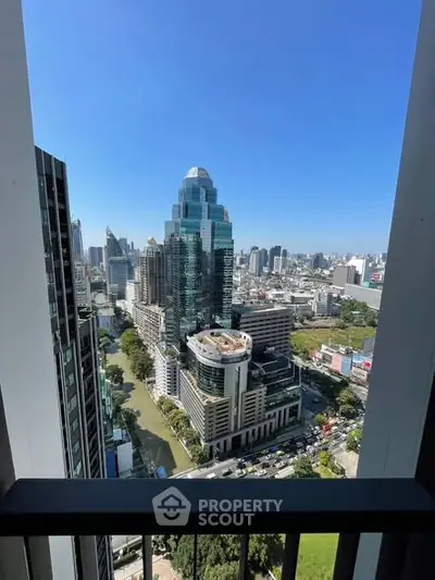 Stunning cityscape view from high-rise balcony with modern skyscrapers and clear blue sky.
