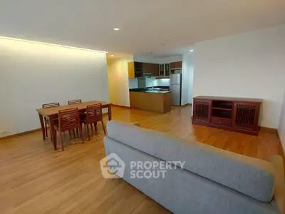 Spacious open-plan living room with modern kitchen and dining area, featuring wooden flooring and contemporary furniture.