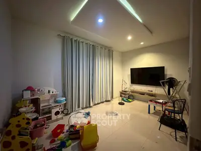 Spacious living room with modern decor and large TV, perfect for family entertainment.