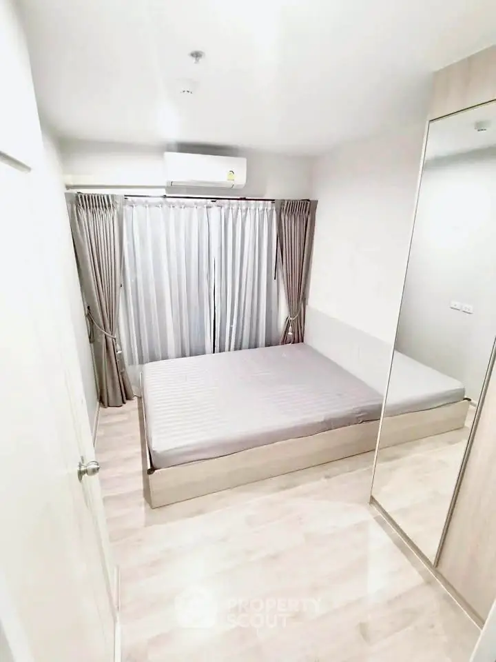 Modern minimalist bedroom with mirrored wardrobe and natural light