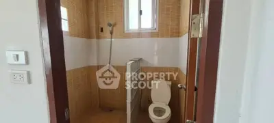 Compact bathroom with shower and toilet in tiled interior