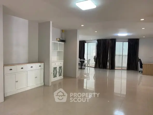 Spacious open-plan living area with modern furnishings and large windows.