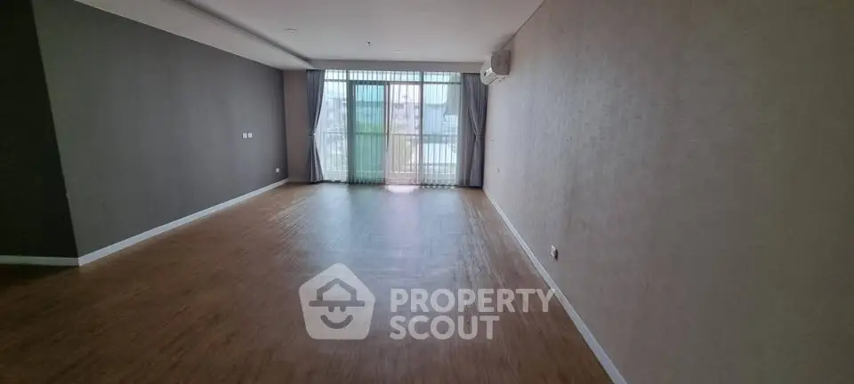Spacious empty living room with large window and wooden flooring