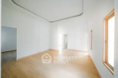 Spacious empty room with wooden flooring and large windows