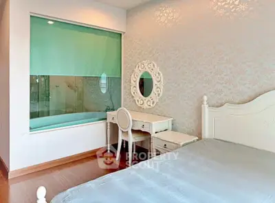 Elegant bedroom with vintage vanity and bathtub view, featuring floral wallpaper and hardwood floors.
