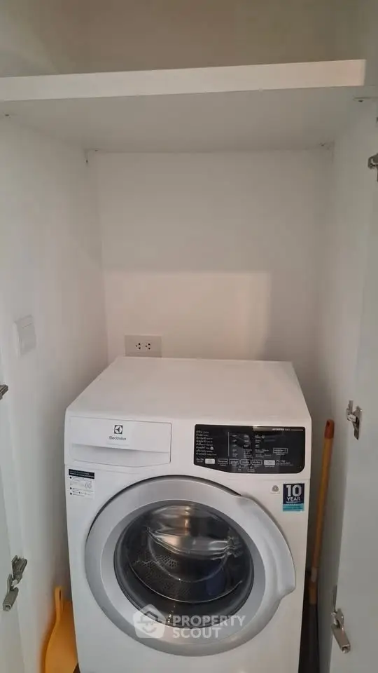 Compact laundry area with modern washing machine in white cabinet