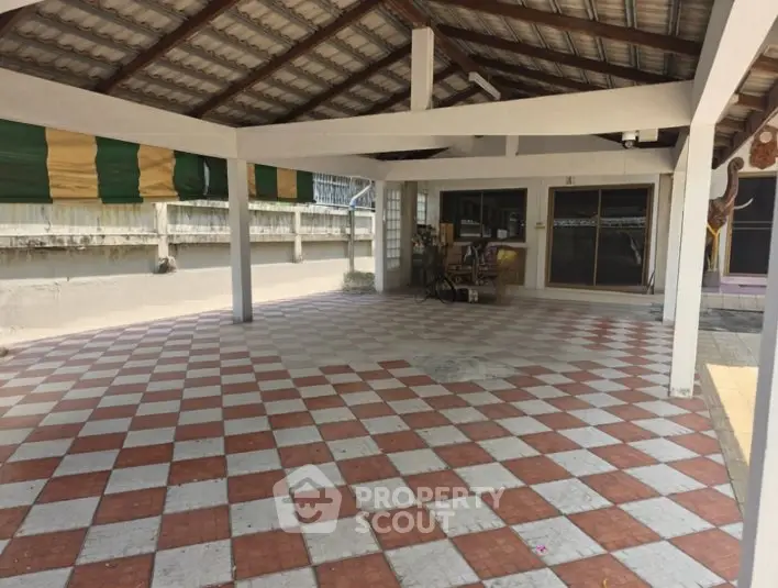 Spacious covered outdoor area with checkered flooring and open layout, ideal for gatherings.