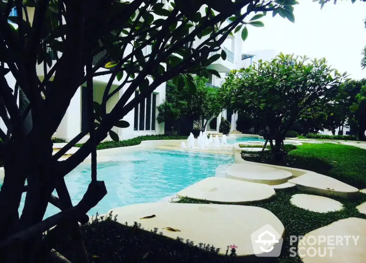 Luxurious garden view with serene pool and lush greenery in modern residential complex.