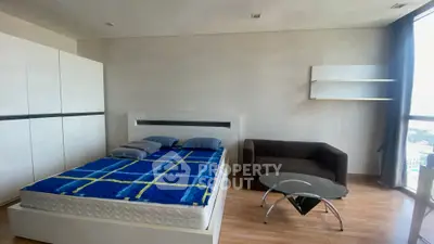 Modern bedroom with stylish furniture and city view, featuring a cozy bed and sleek decor.