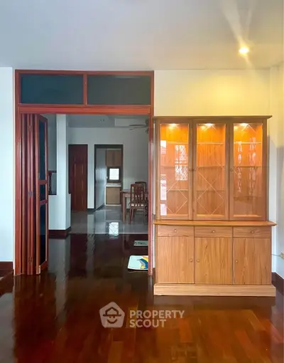 Spacious living area with elegant wooden flooring and built-in display cabinet.