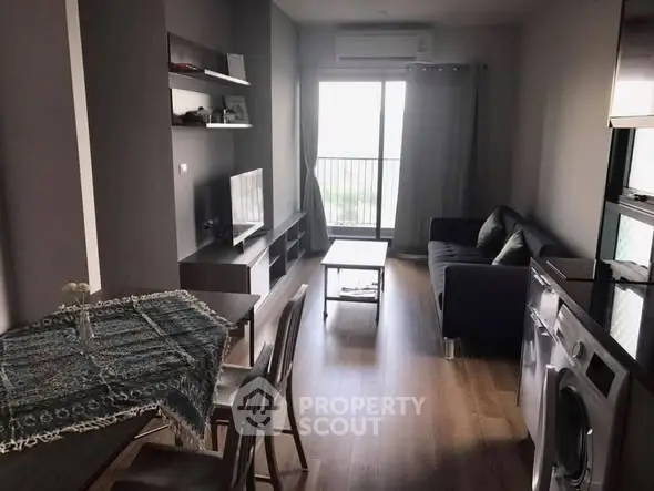 Modern living room with balcony, featuring sleek furniture and appliances.