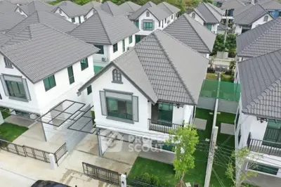 Aerial view of a modern residential housing estate with uniform design, showcasing the neat arrangement of homes with well-manicured lawns and driveways.
