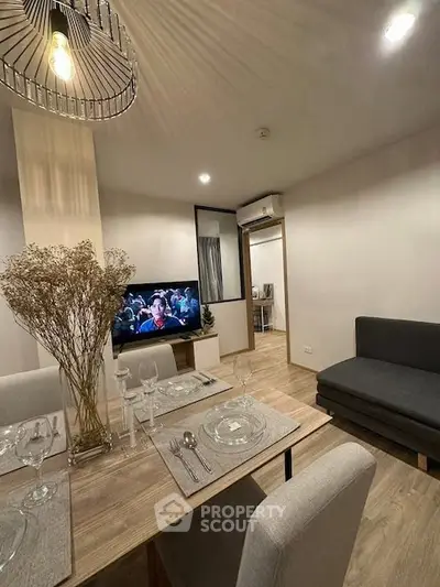 Modern living room with stylish decor and open dining area, featuring elegant lighting and cozy seating.