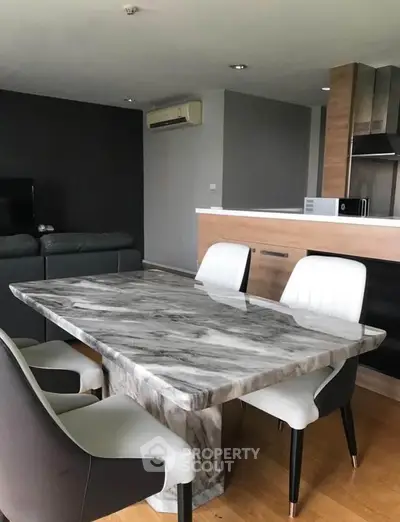 Modern dining area with marble table and stylish chairs in open-plan living space.