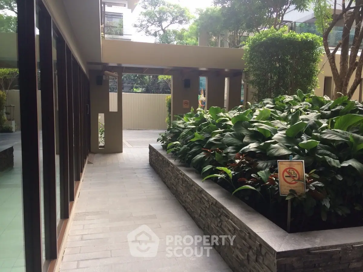 Elegant outdoor garden area with lush greenery in modern residential complex.