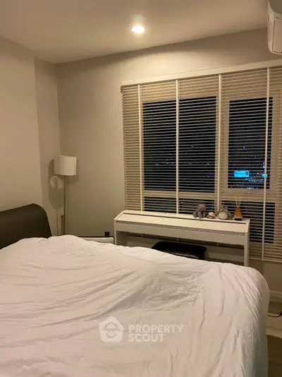 Cozy bedroom with modern decor and large window, perfect for relaxation and comfort.