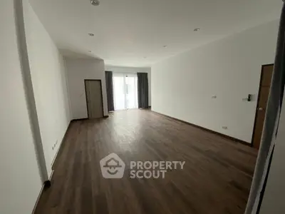 Spacious empty room with wooden flooring and large windows, ideal for customization.