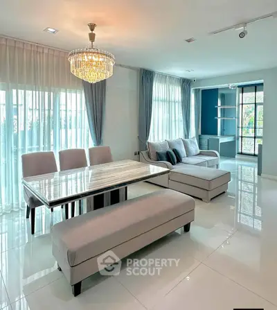 Elegant living room with chandelier, modern furniture, and large windows for natural light.