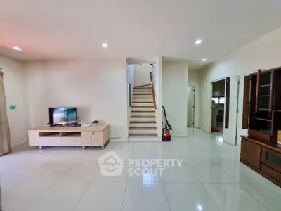 Spacious living room with modern staircase and sleek tile flooring